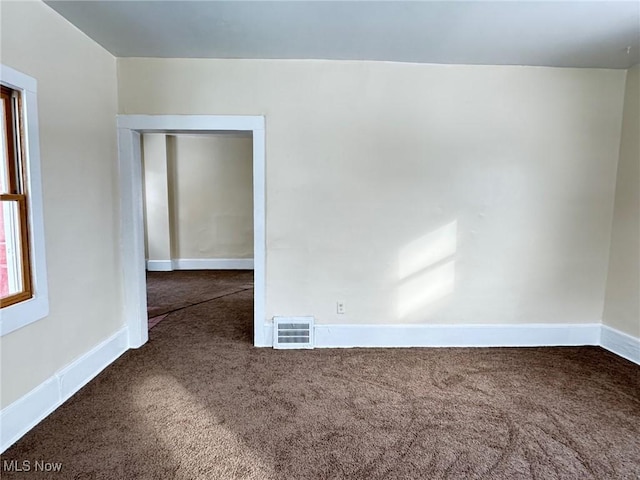 unfurnished room featuring dark carpet