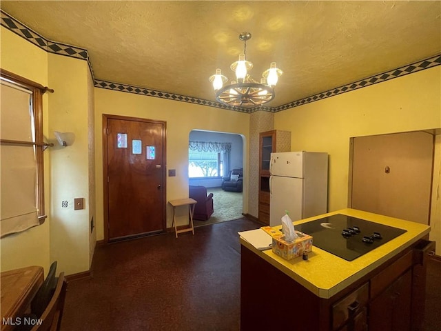 kitchen featuring black electric cooktop, white fridge, a textured ceiling, and a notable chandelier