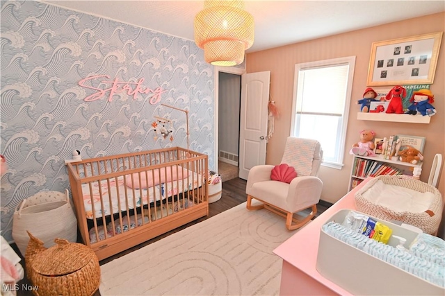 bedroom featuring a crib and hardwood / wood-style flooring