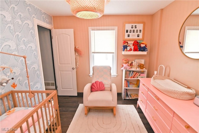 bedroom featuring a crib and dark wood-type flooring