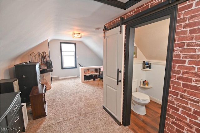 carpeted bedroom featuring a barn door and lofted ceiling