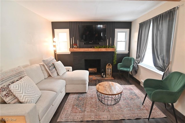 living room featuring dark hardwood / wood-style floors, a wealth of natural light, and a brick fireplace