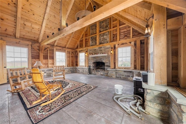 living room featuring beamed ceiling, high vaulted ceiling, a stone fireplace, and wood ceiling