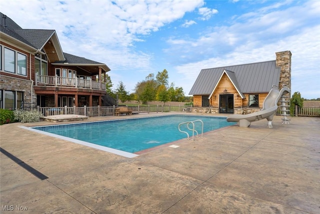 view of swimming pool featuring a water slide and a patio