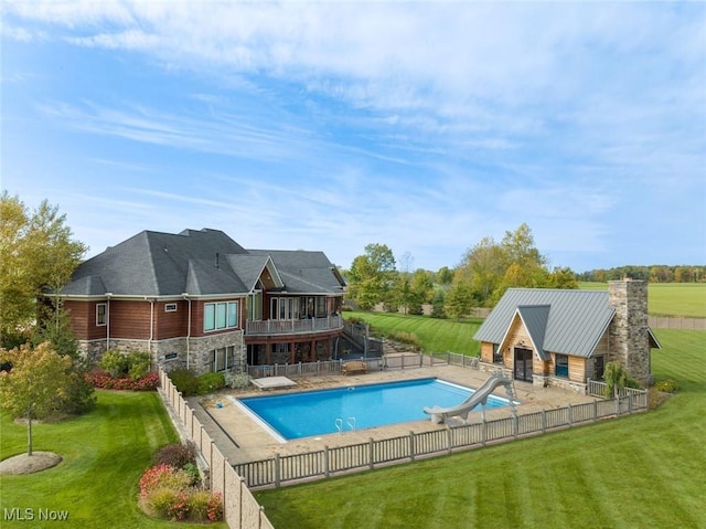 view of swimming pool featuring a lawn, a diving board, a water slide, and a patio