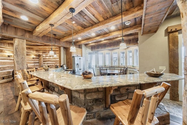 kitchen featuring beamed ceiling, light stone counters, hanging light fixtures, and log walls