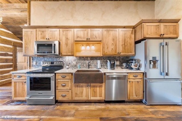 kitchen with appliances with stainless steel finishes, hardwood / wood-style flooring, tasteful backsplash, and sink