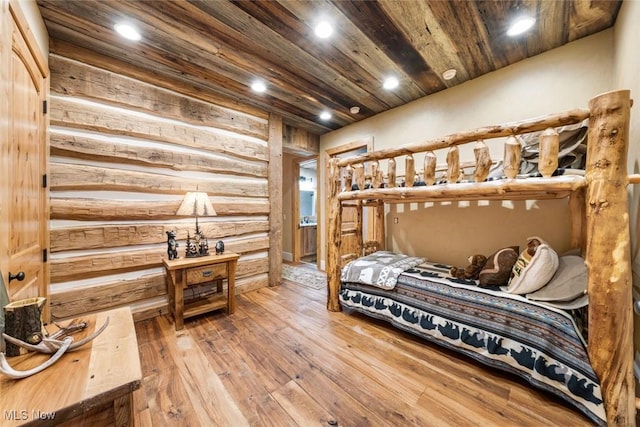 bedroom with hardwood / wood-style flooring and rustic walls