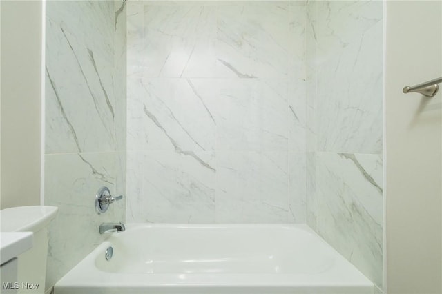 bathroom with tiled shower / bath combo and toilet