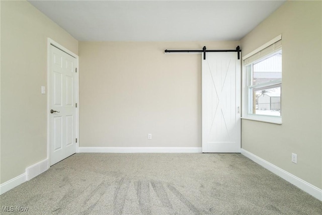 carpeted empty room featuring a barn door