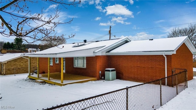 snow covered house featuring central AC