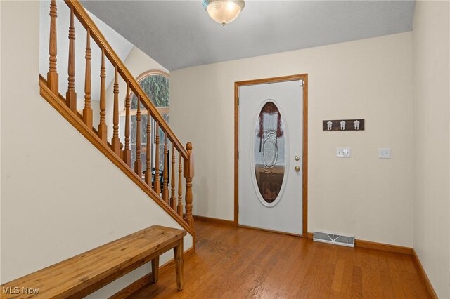 foyer entrance with baseboards, wood finished floors, and stairway
