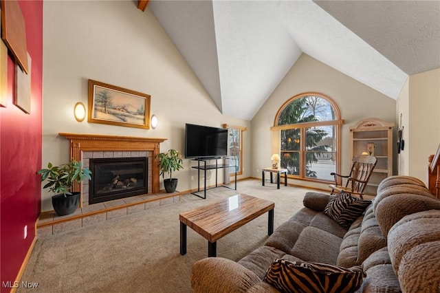living room featuring carpet flooring, a tiled fireplace, high vaulted ceiling, and baseboards