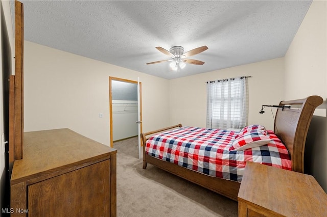 bedroom with ceiling fan, a spacious closet, a textured ceiling, light carpet, and a closet