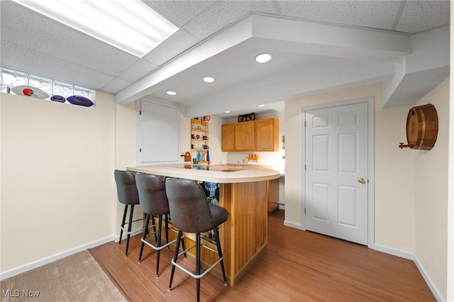 kitchen featuring a drop ceiling, kitchen peninsula, and a breakfast bar area