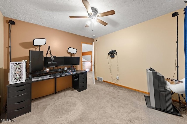 carpeted office space with a ceiling fan, a textured ceiling, and baseboards