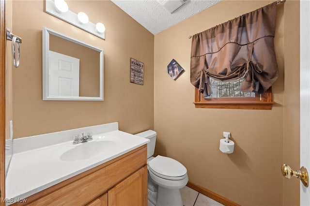 bathroom with toilet, vanity, a textured ceiling, tile patterned floors, and baseboards
