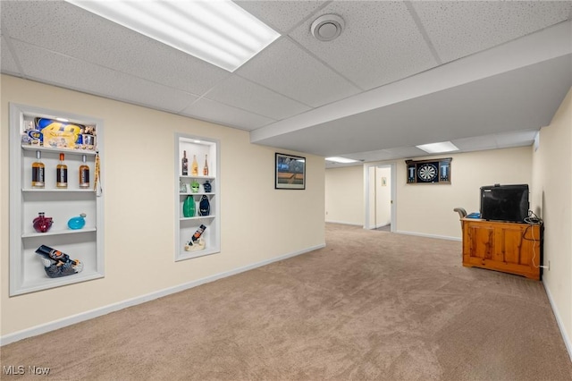 finished basement with carpet flooring, a drop ceiling, and baseboards