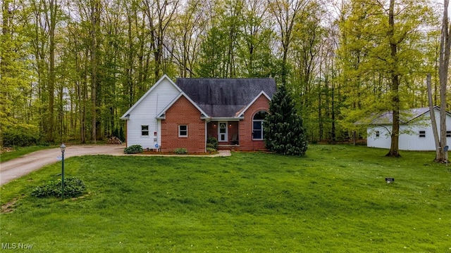 ranch-style house with brick siding, a front lawn, an outdoor structure, and driveway