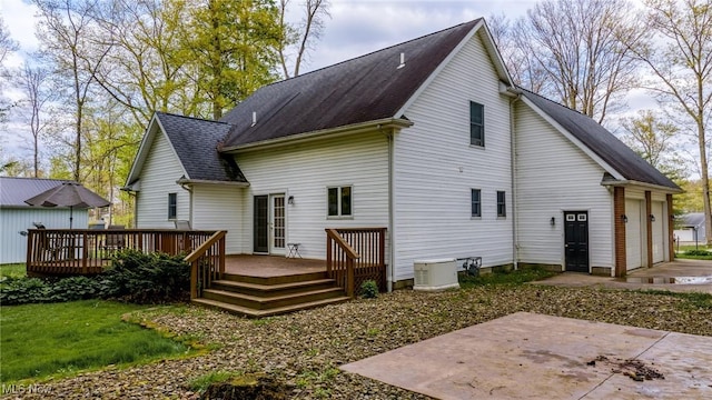 rear view of property with a wooden deck, a patio area, roof with shingles, and a garage