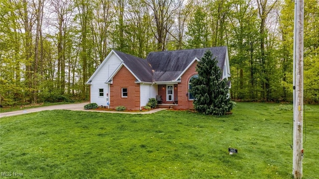 view of front of house featuring brick siding, a front lawn, and driveway