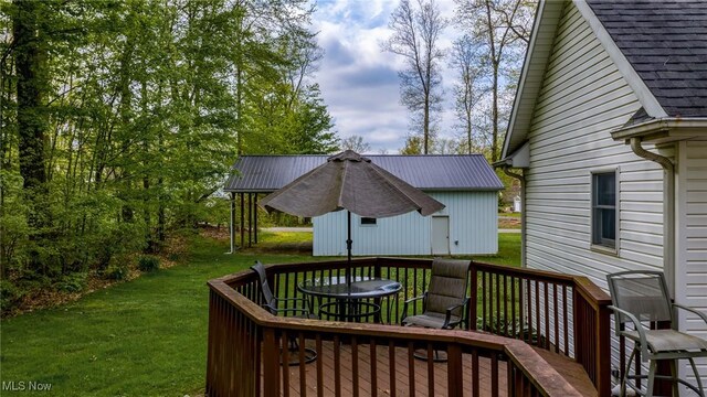 wooden deck featuring a lawn and an outbuilding