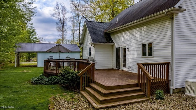 rear view of house with a deck, a lawn, and a shingled roof