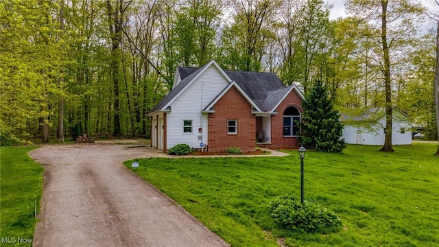 view of front of home with asphalt driveway, a front yard, and brick siding
