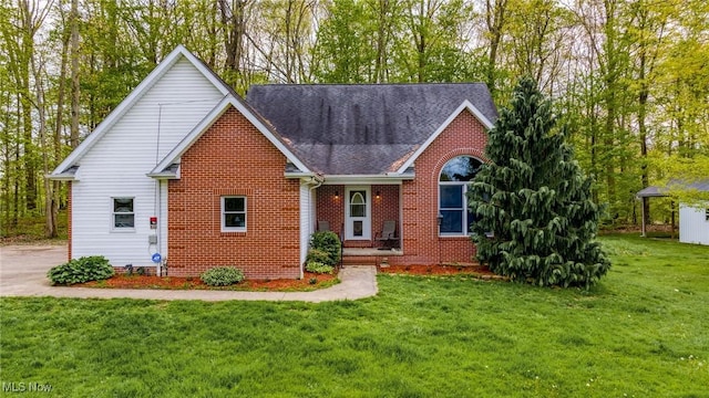 traditional home with brick siding, a front yard, and a shingled roof