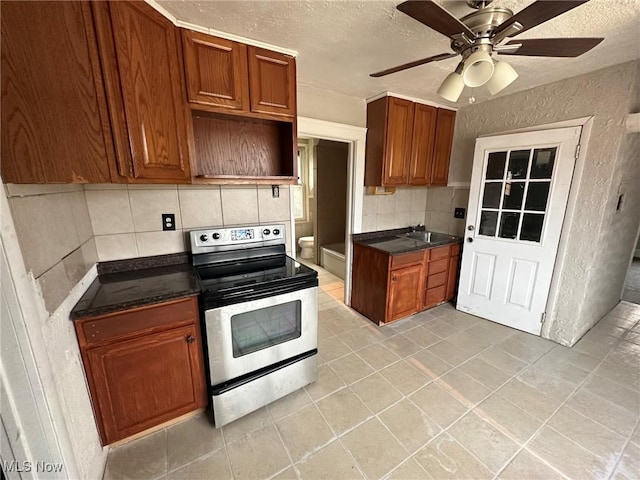 kitchen featuring decorative backsplash, a textured ceiling, stainless steel electric range oven, and ceiling fan