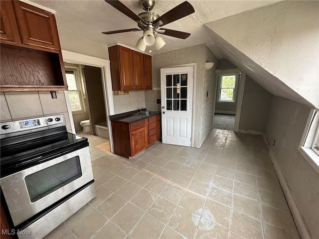 kitchen featuring decorative backsplash, stainless steel range with electric stovetop, ceiling fan, sink, and lofted ceiling