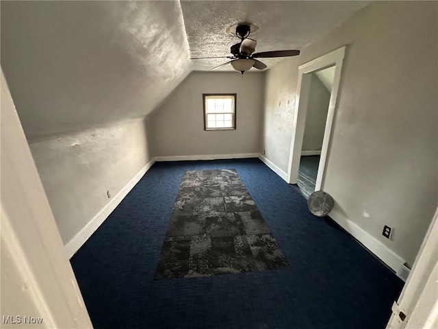 bonus room with dark colored carpet, a textured ceiling, ceiling fan, and lofted ceiling