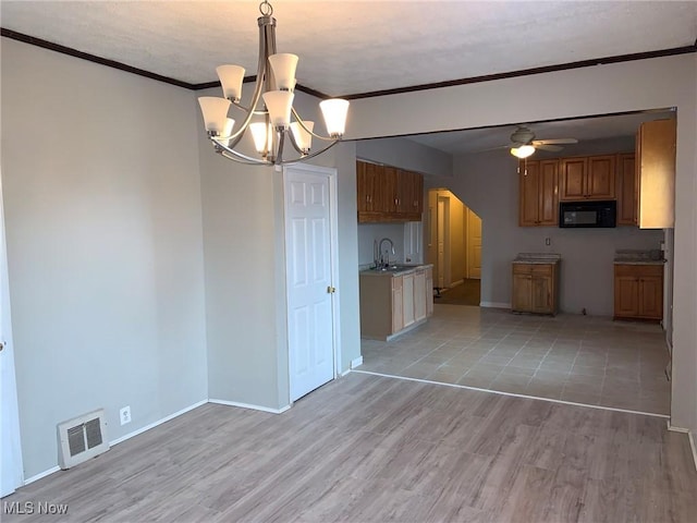 kitchen featuring ceiling fan with notable chandelier, sink, hanging light fixtures, light hardwood / wood-style flooring, and ornamental molding