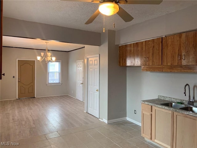 kitchen with a textured ceiling, ceiling fan with notable chandelier, sink, and hanging light fixtures