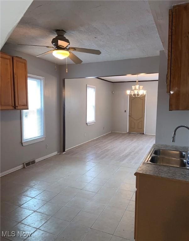 kitchen featuring sink, hanging light fixtures, and ceiling fan with notable chandelier