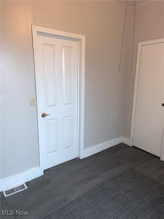 spare room with dark carpet