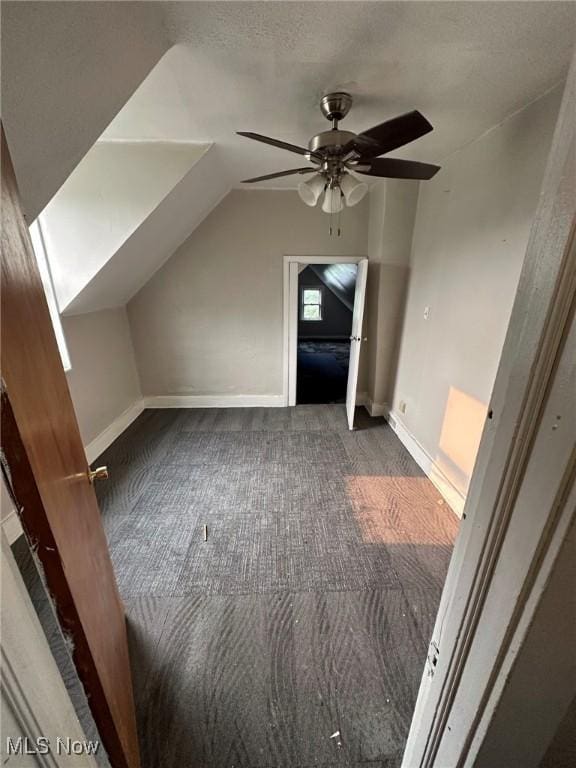 additional living space with dark colored carpet, ceiling fan, and lofted ceiling