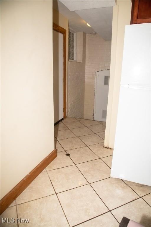 hallway with brick wall and light tile patterned floors