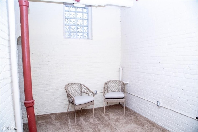 sitting room featuring carpet floors and brick wall