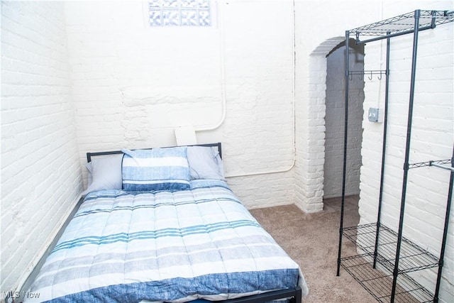 bedroom featuring brick wall and carpet