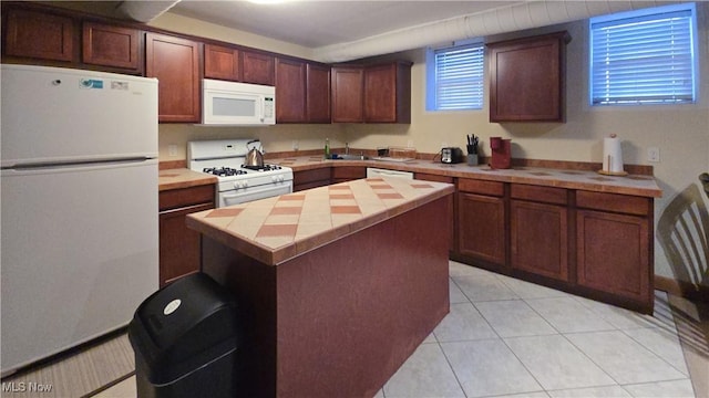 kitchen with sink, white appliances, a center island, and light tile patterned flooring