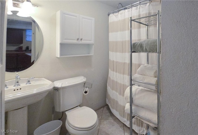 bathroom featuring sink, toilet, a shower with curtain, and tile patterned flooring