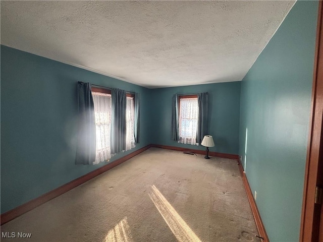 carpeted empty room with a textured ceiling