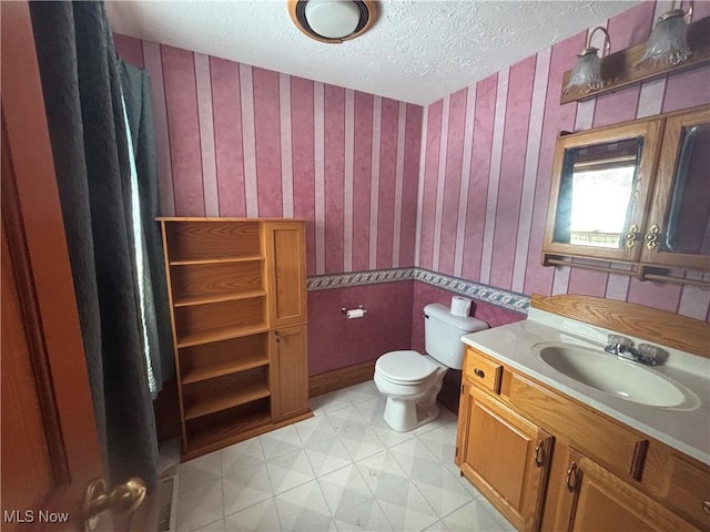 bathroom with vanity, a textured ceiling, and toilet