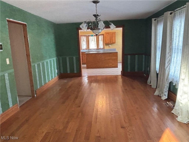 unfurnished dining area featuring hardwood / wood-style floors and a chandelier