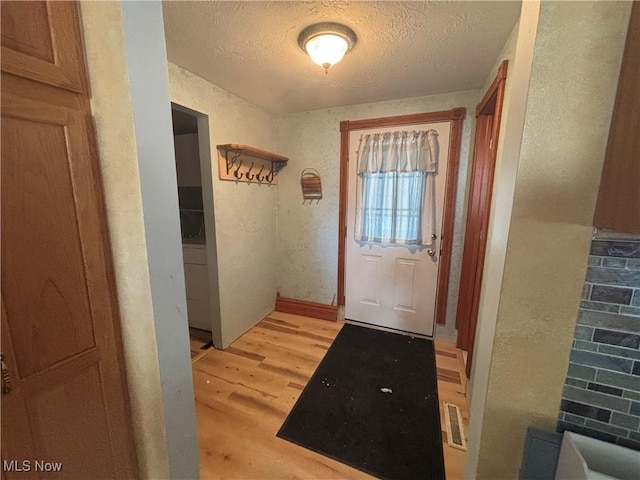 entryway with a textured ceiling and light hardwood / wood-style floors