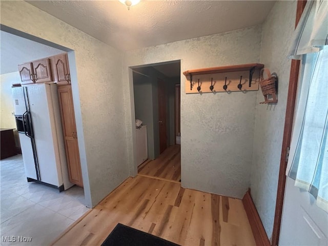 hallway with separate washer and dryer and light hardwood / wood-style flooring