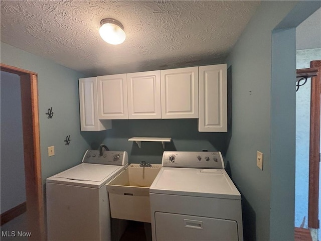 clothes washing area featuring washer and clothes dryer, cabinets, a textured ceiling, and sink