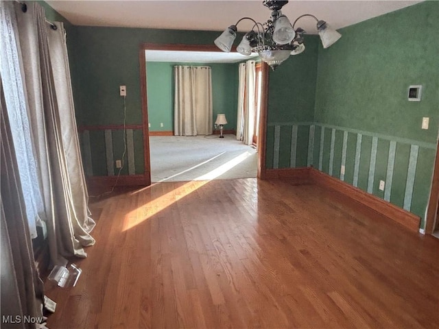 unfurnished dining area featuring hardwood / wood-style flooring and an inviting chandelier