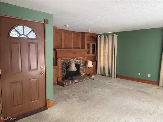 unfurnished living room with light colored carpet, a textured ceiling, and a brick fireplace